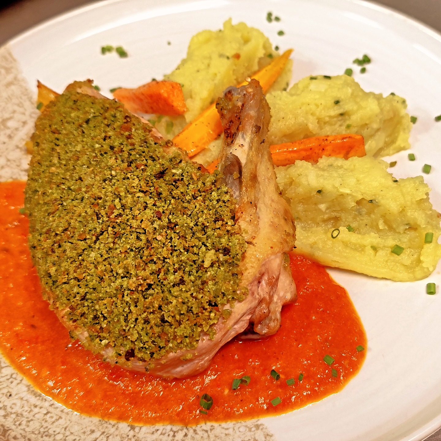 Une cuisse de volaille en croûte d'herbes sur un coulis de poivron, avec des légumes